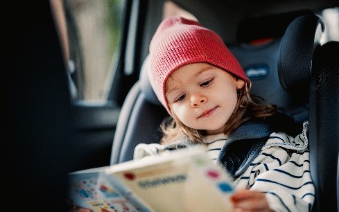 child in car seat reading a book