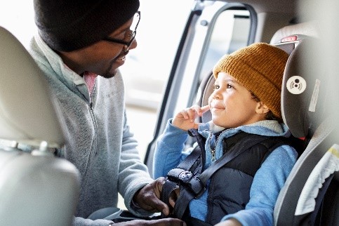 young boy in car seat with man buckling him in