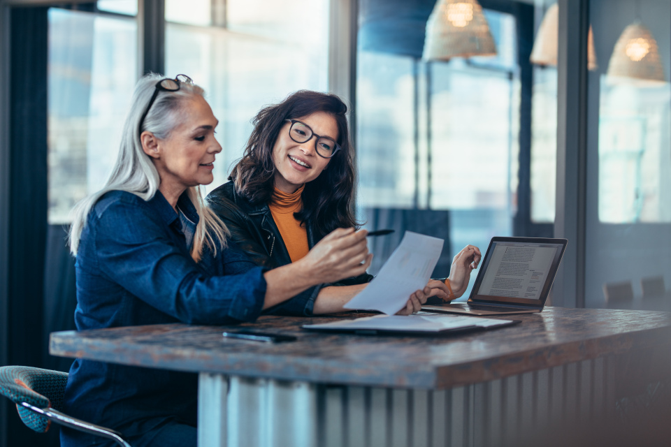 two people looking at documents and a laptop